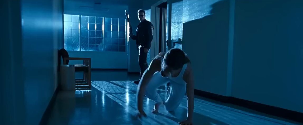 A blue-lit hospital corridor; a woman on the floor, a figure standing behind her.