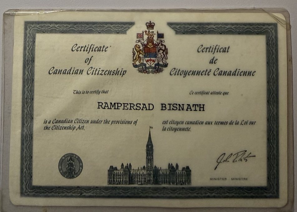 A wallet-size Certificate of Canadian Citizenship in English and French, with the Canadian coat of arms, a drawing of Parliament and the name Rampersad Bisnath.